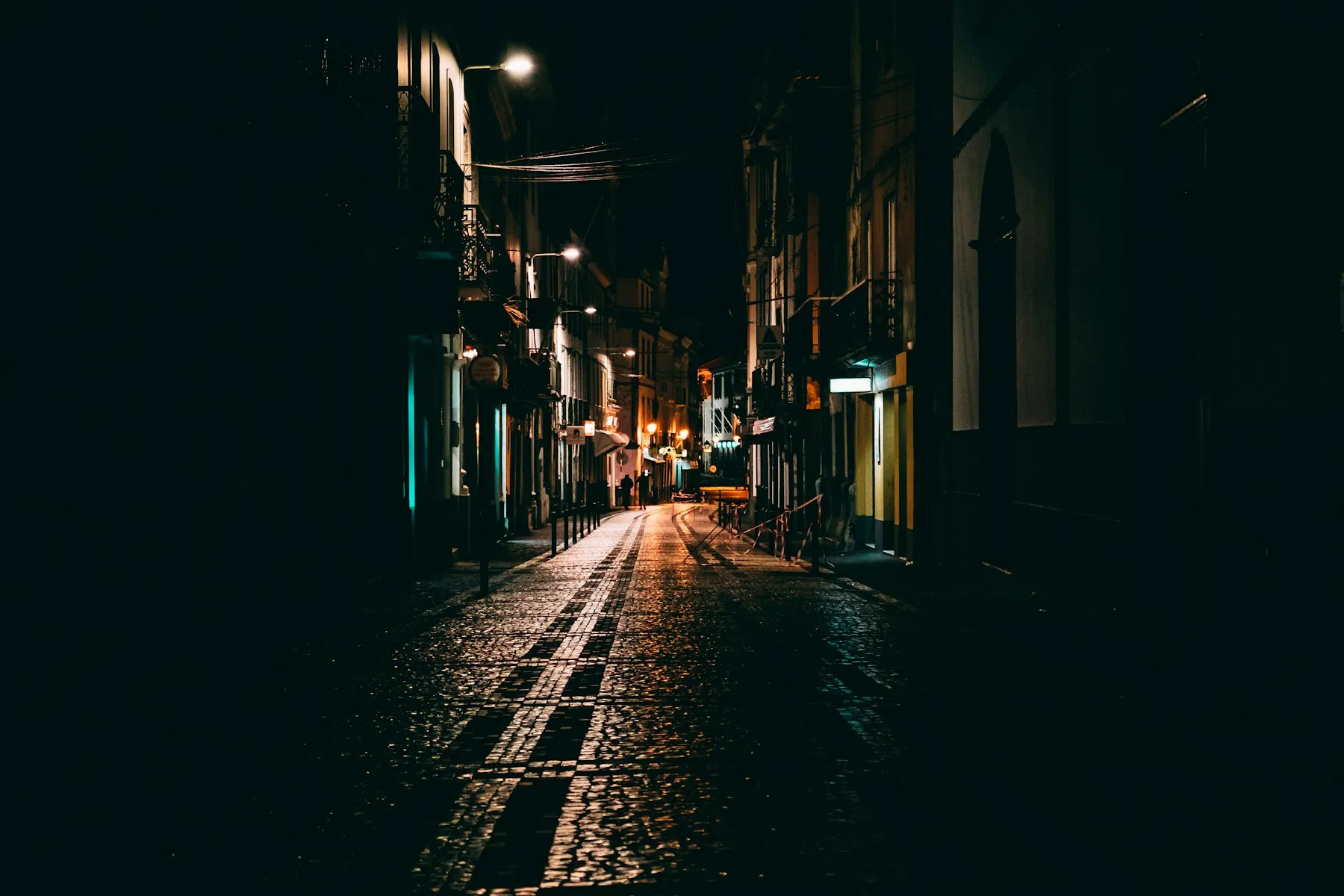 Calle estrecha de noche iluminada por farolas