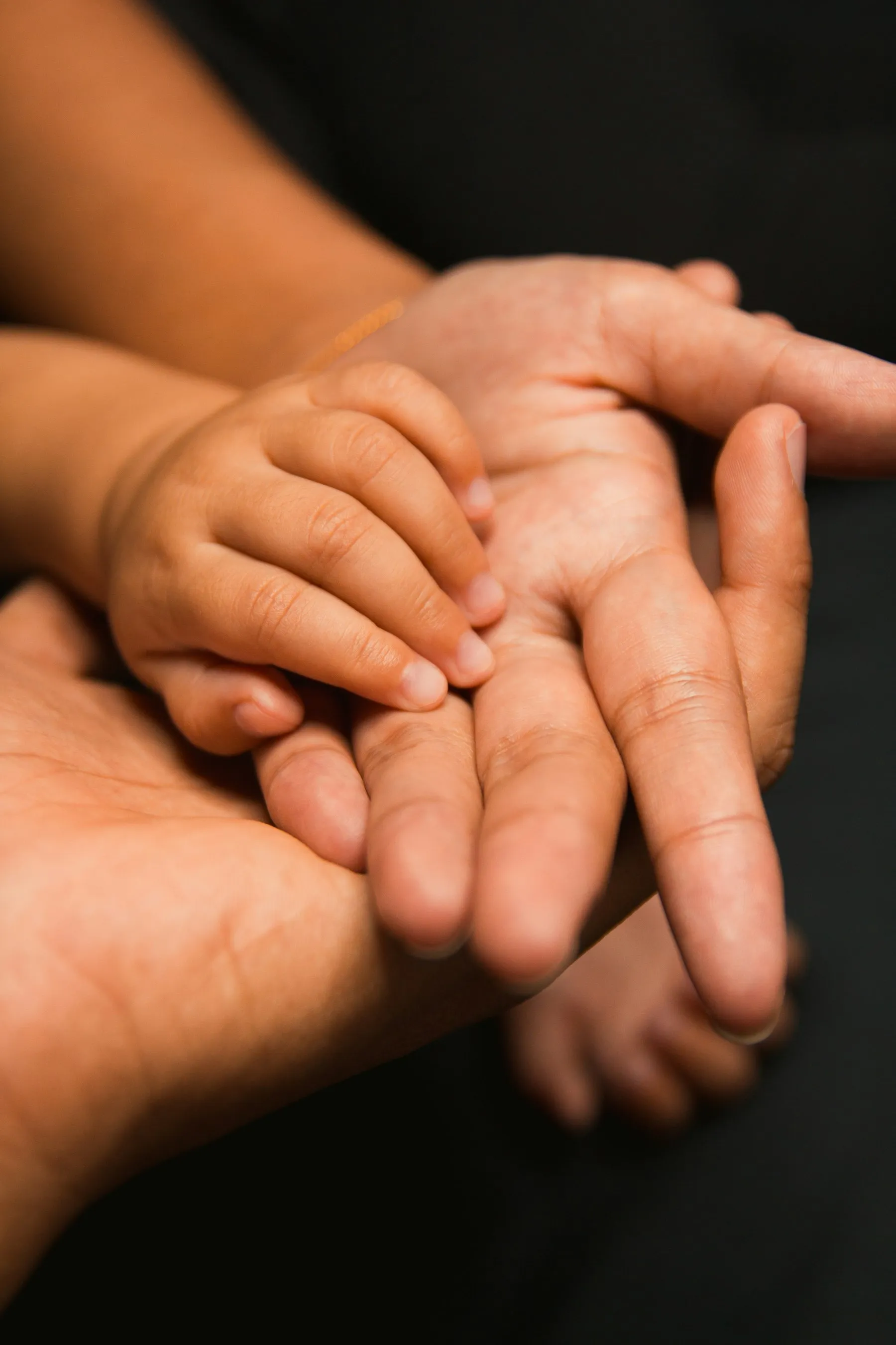 Mano de un niño sobre la mano de un adulto